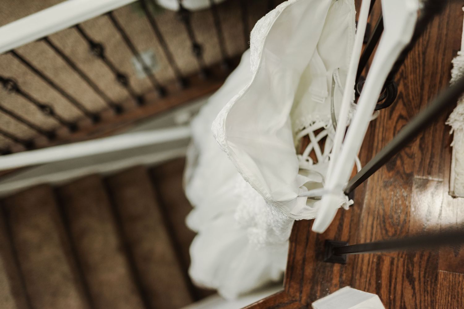 Close-up detail of white wedding dress fabric and lace against wooden background.