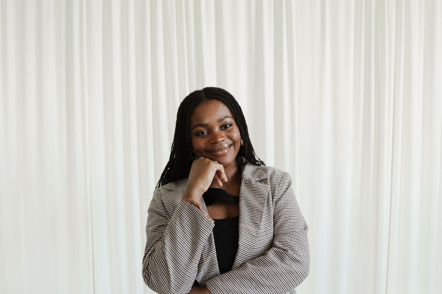 Thoughtful creative professional in gray blazer poses against white backdrop in minimalist studio space.