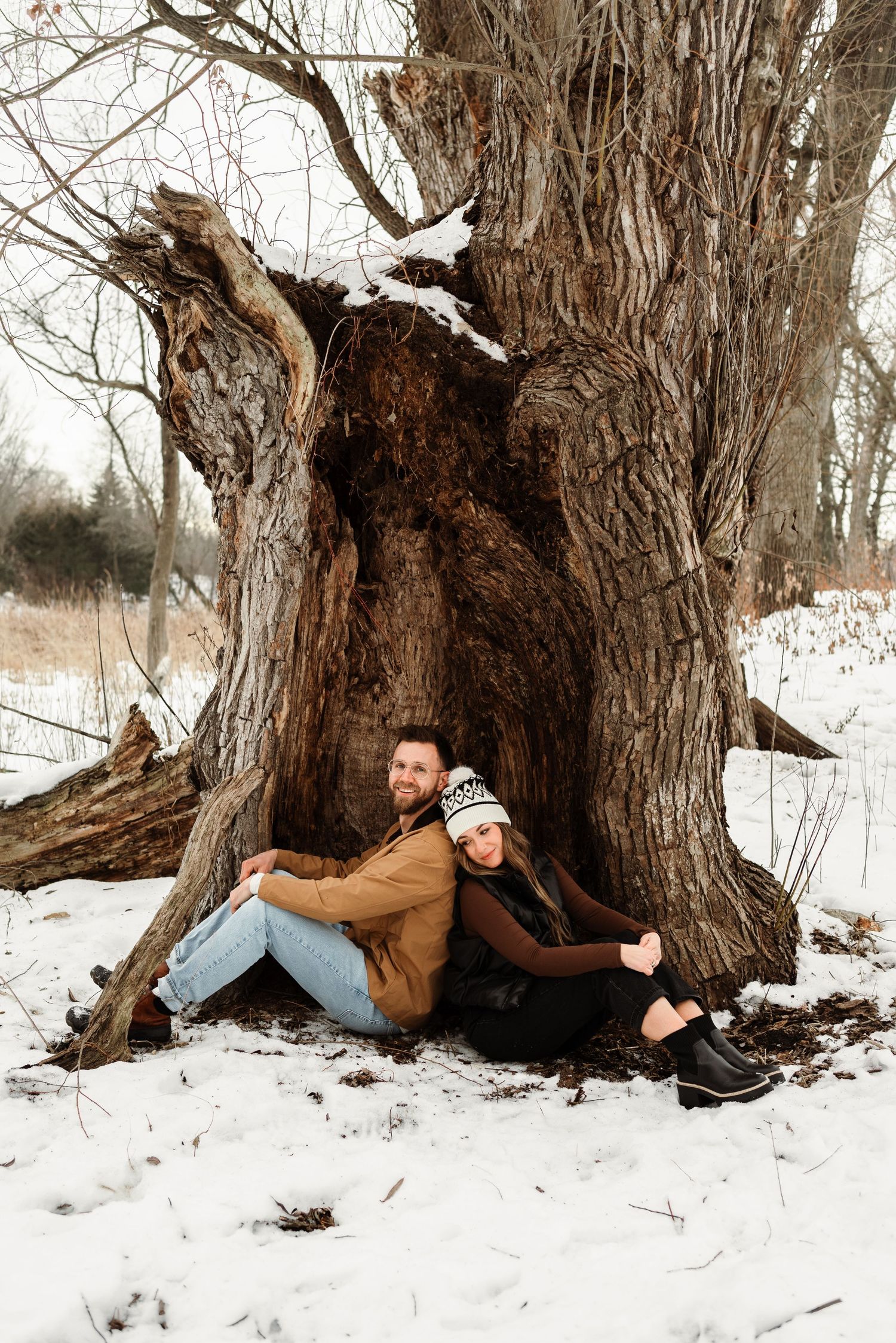 couple siting down next to tree back-to-back in Plymouth Minnesota