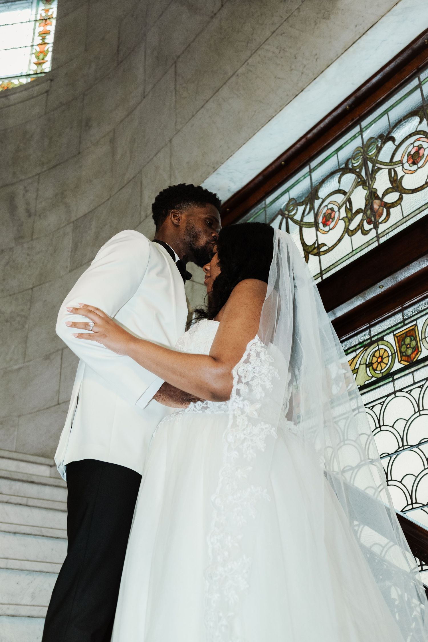Elegant wedding photos captured in a church corridor with stained glass windows.