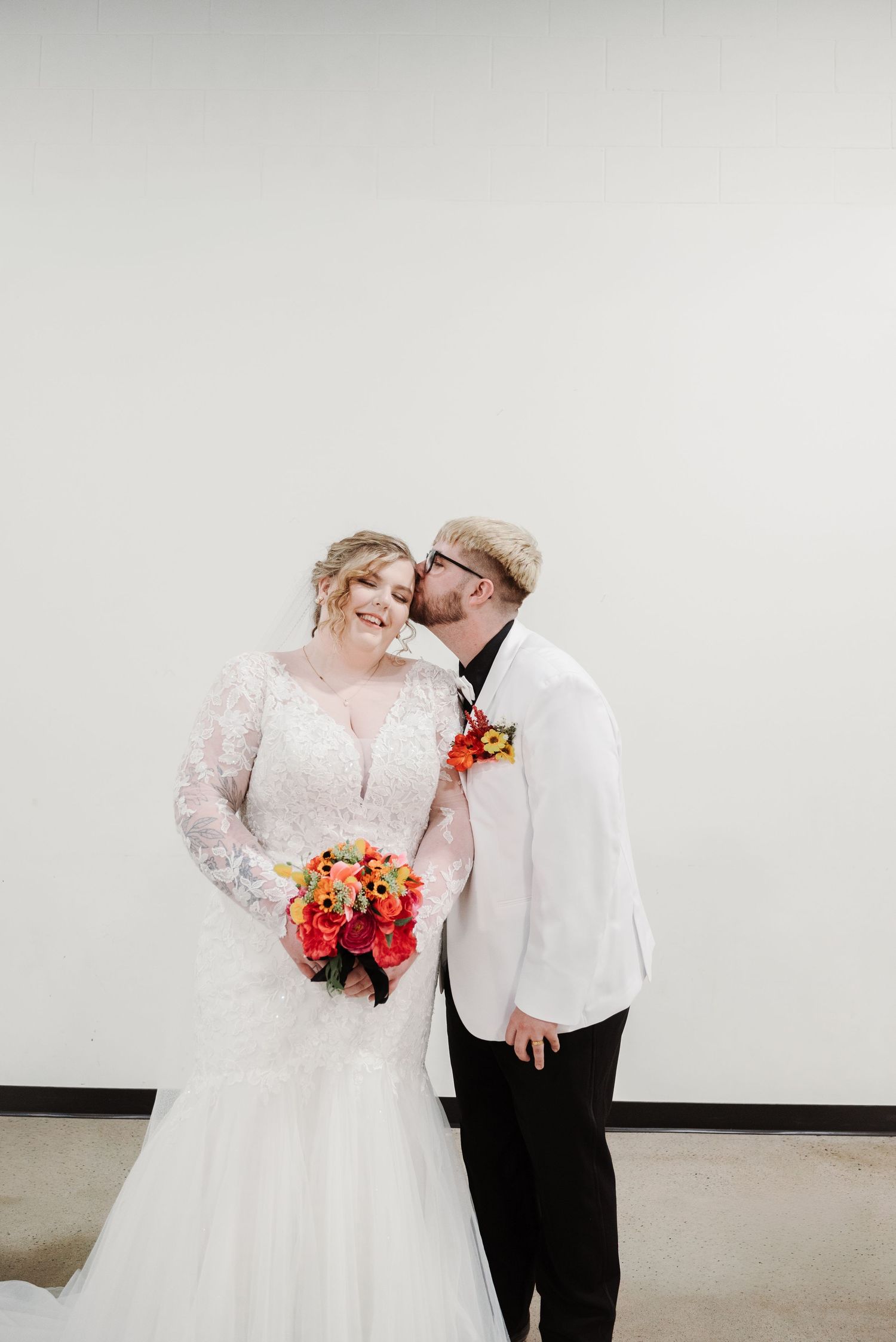 A romantic wedding photoshoot with a couple in white attire sharing intimate moments and holding vibrant bouquets.