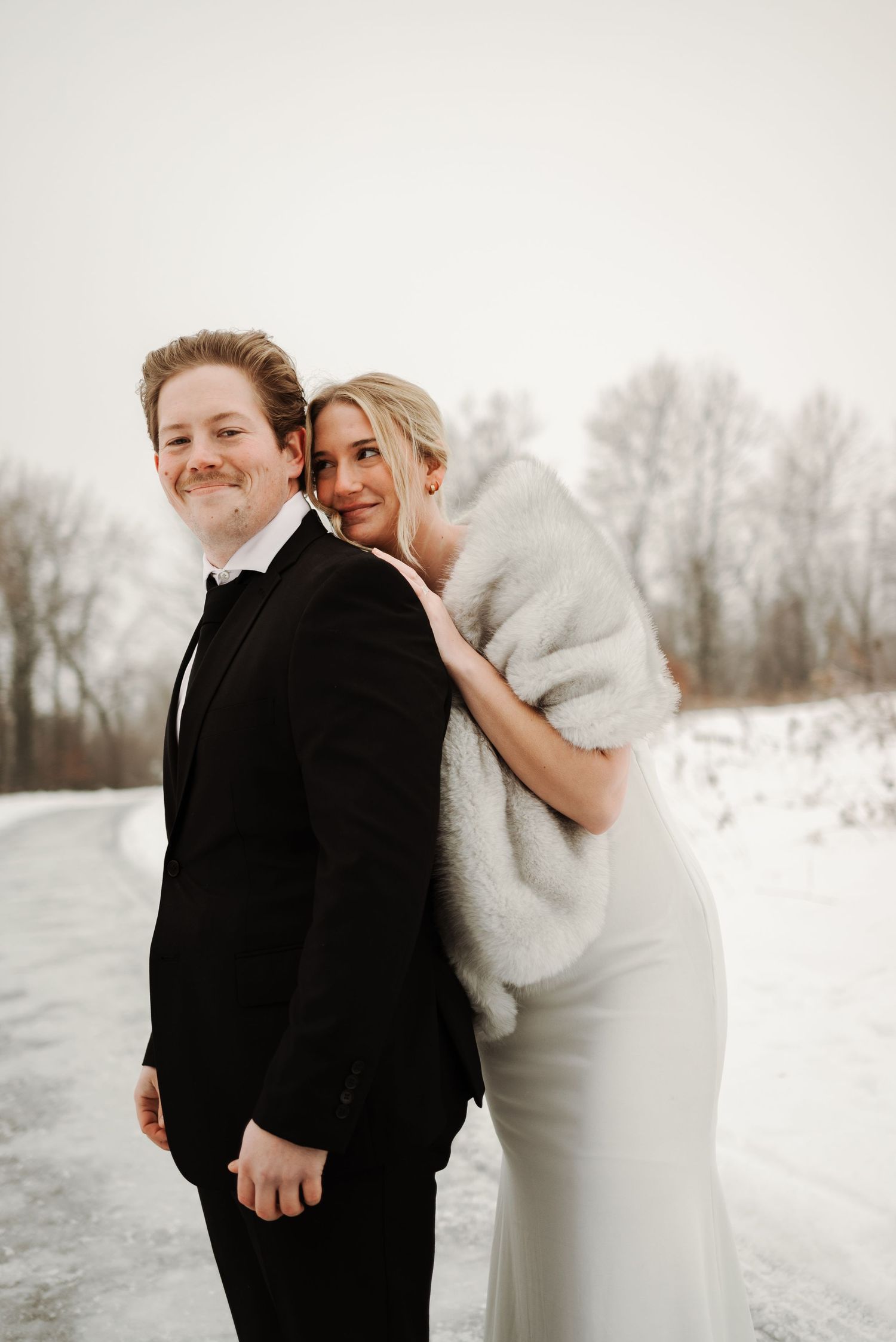Playful winter wedding photos showing a couple laughing in the snow.