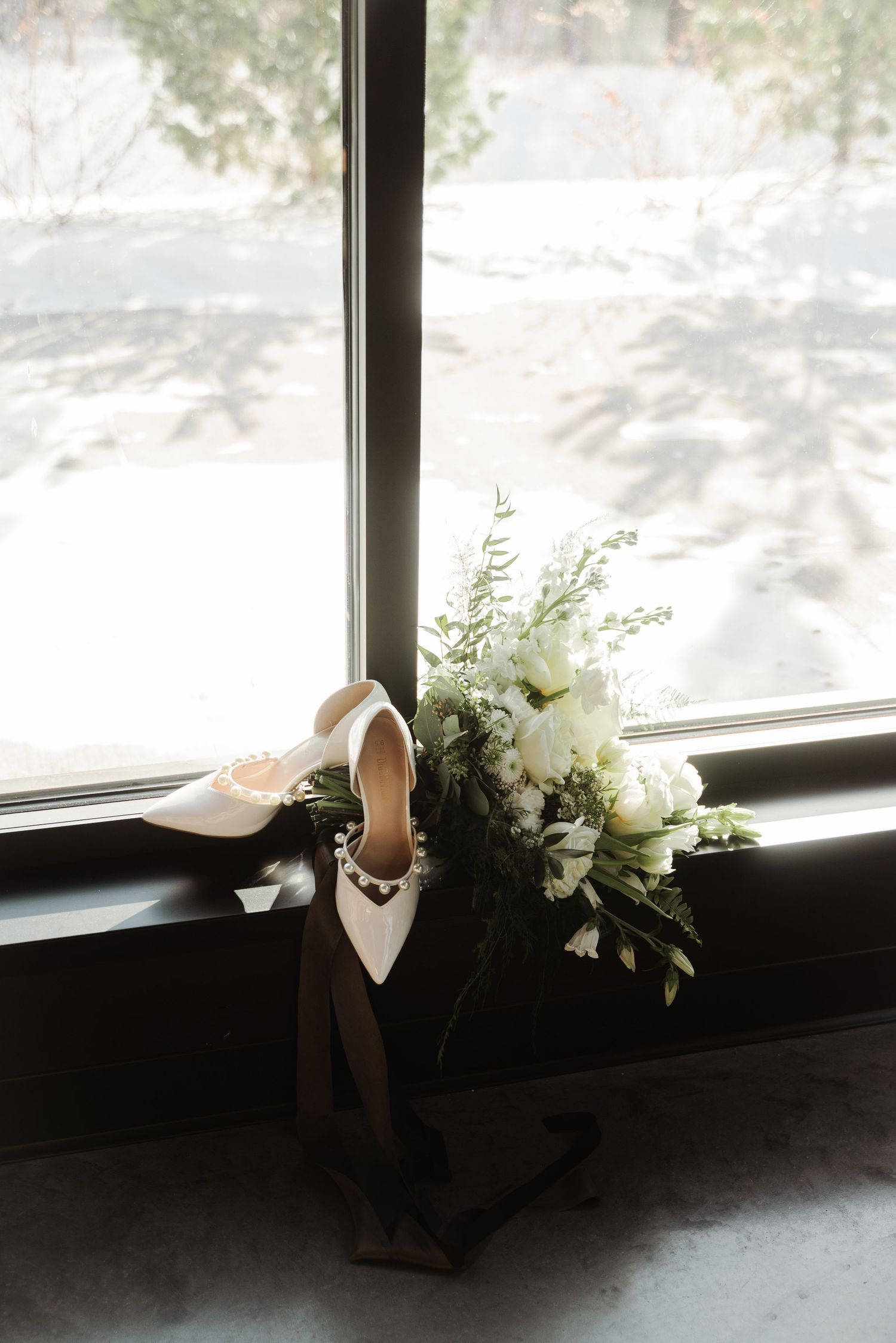 White floral arrangements decorating a windowsill with snowy outdoor scenery.