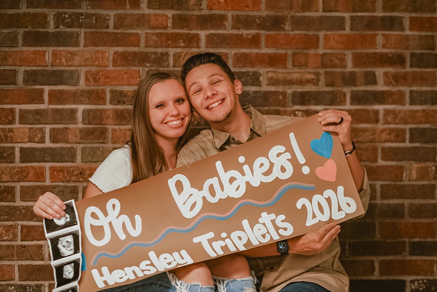 Wooden signs with text against a rustic brick wall background.