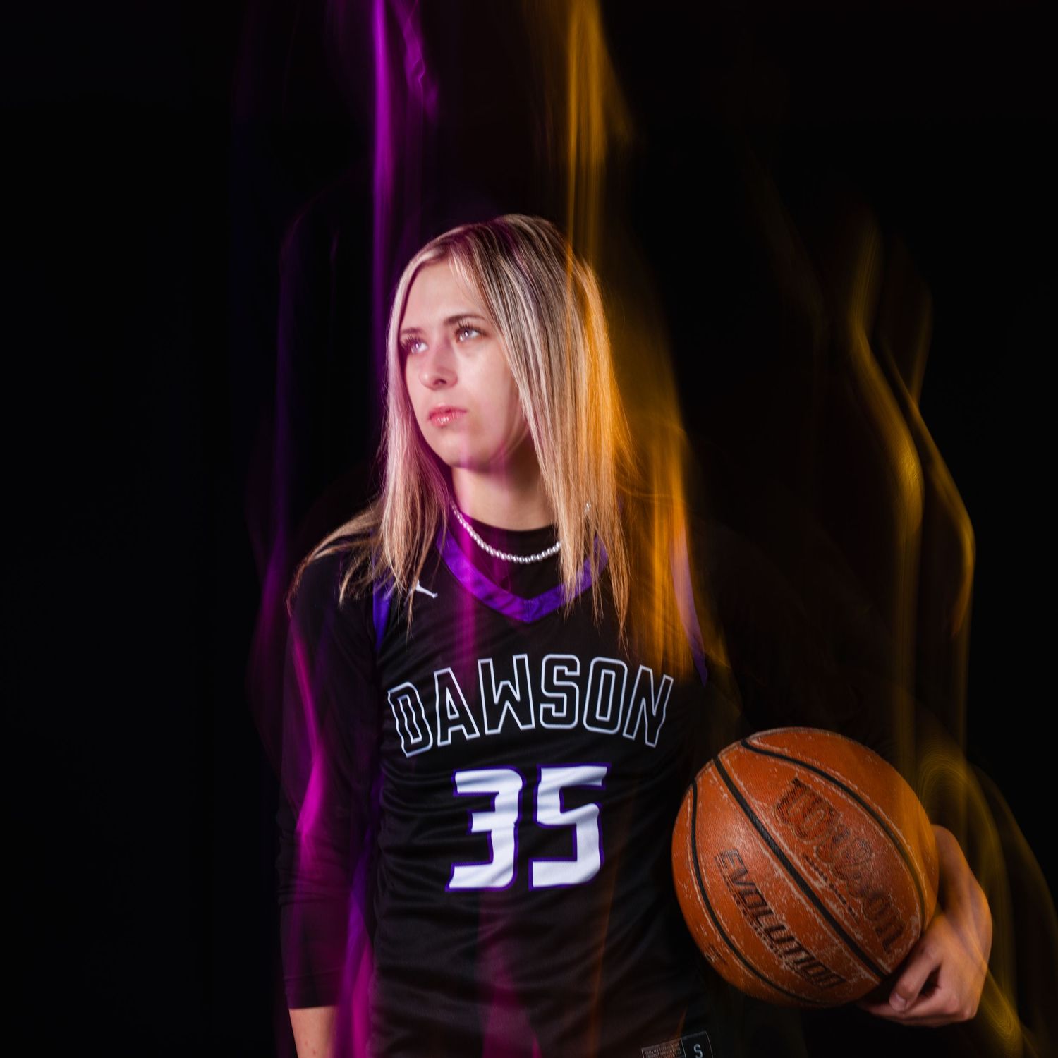 Female basketball player in Dawson #35 jersey holding a Wilson ball, dramatic purple and gold light painting background.