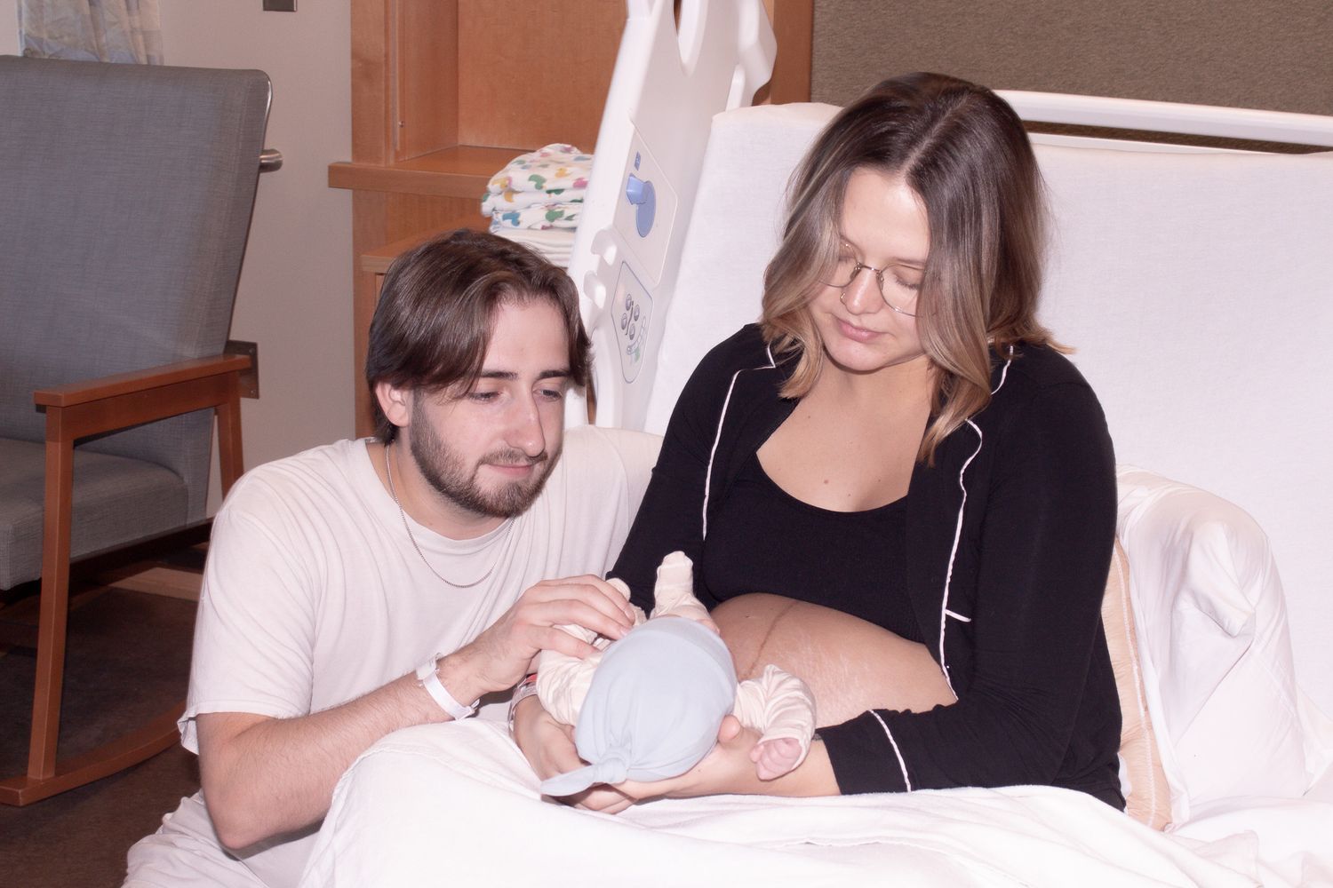 Couple sitting in hospital bed lovingly admiring their newborn baby.