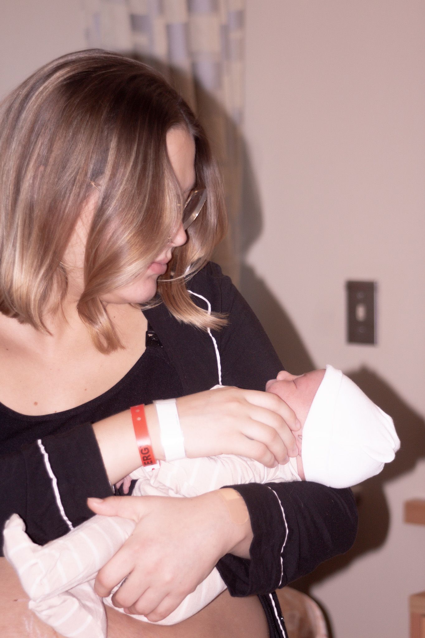 New mother in hospital room holding and gazing lovingly at her newborn baby.