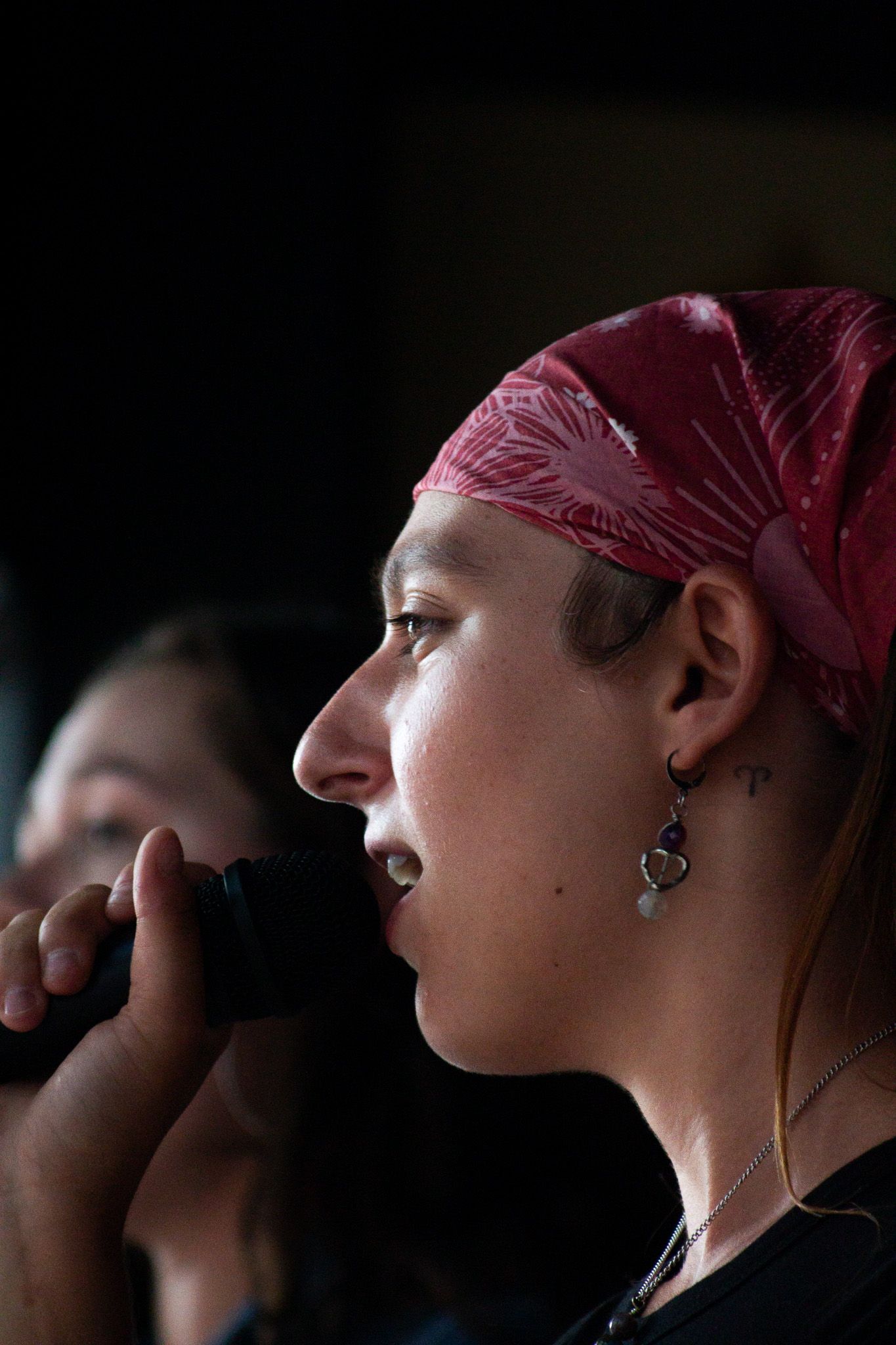 Female singer performing with microphone wearing red bandana at live music event.