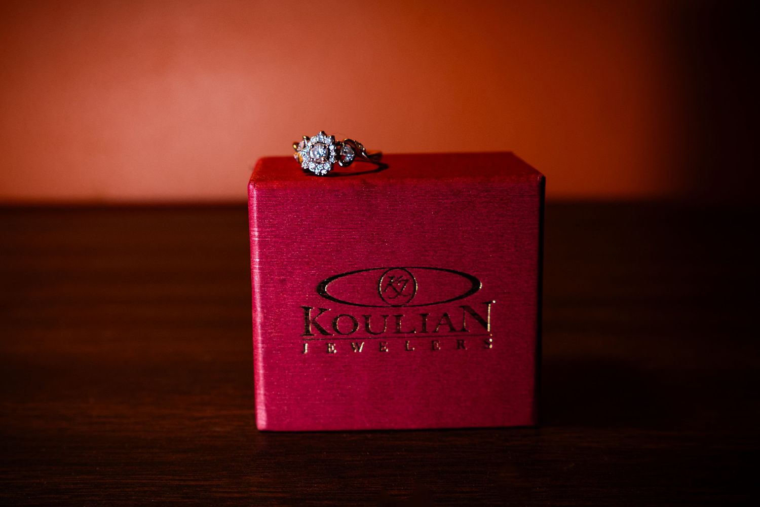 Diamond engagement ring displayed on a red Kolleys Jewelers ring box on a wooden surface.