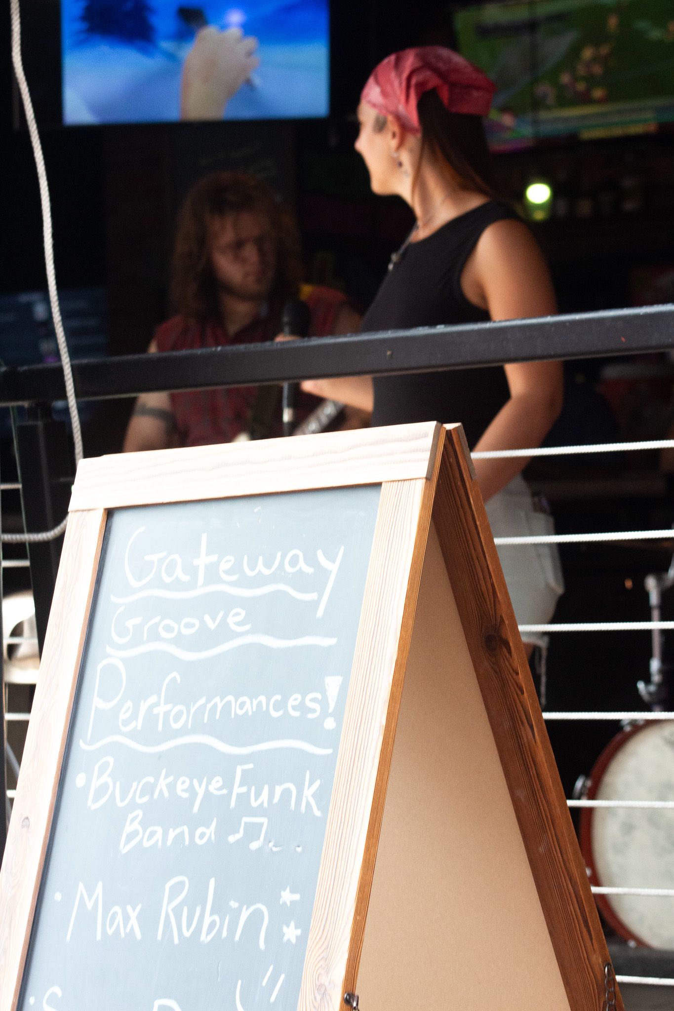 Chalkboard sign advertising Gateway Groove Performances featuring Buckeye Funk Band and Max Rubin at outdoor venue.