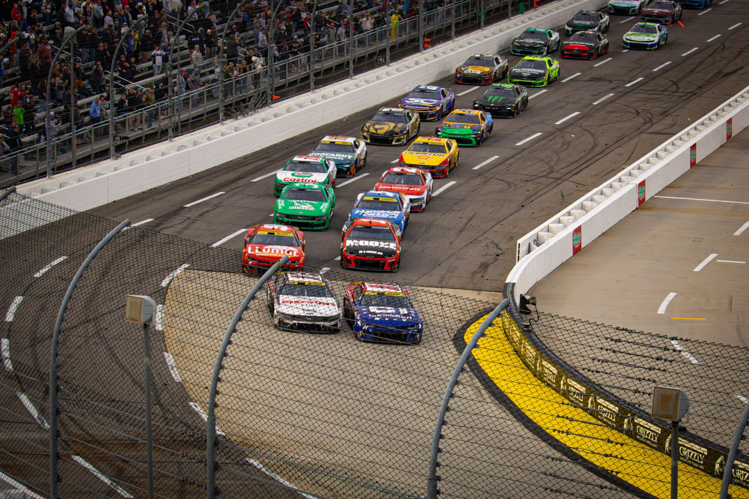 Multiple race cars battle for position on Martinsville Speedway's iconic paperclip-shaped track.