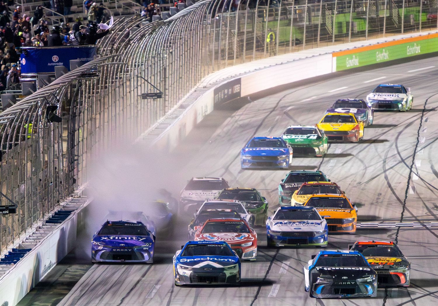 Multiple stock cars racing in tight formation around Echo Park Speedway