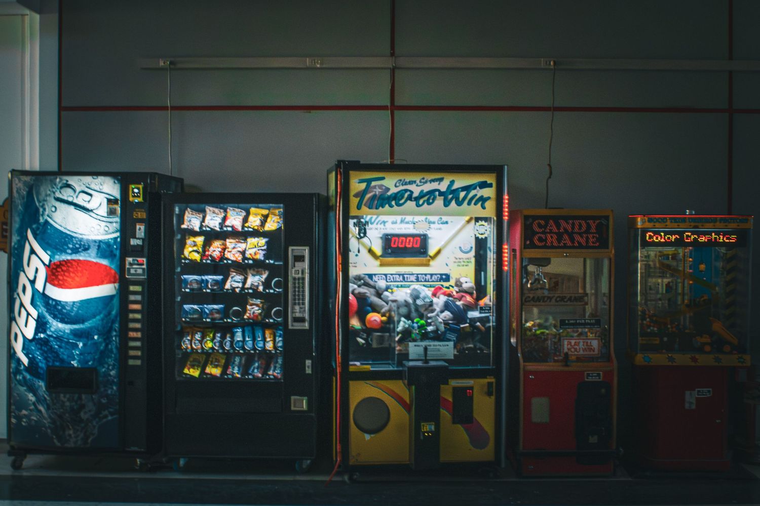 Row of vintage arcade games and vending machines including Pepsi and classic gaming cabinets.