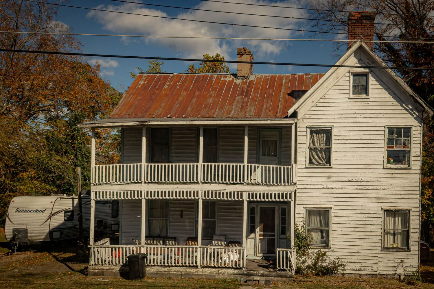 Series of white clapboard houses with porches lined up along a rural road.