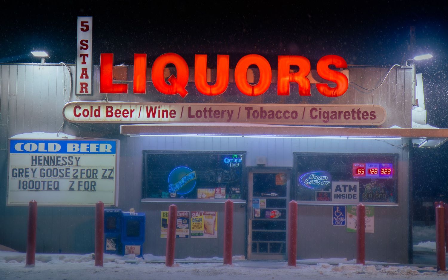 Neon liquor store sign glowing at night advertising cold beer, wine, and tobacco products.