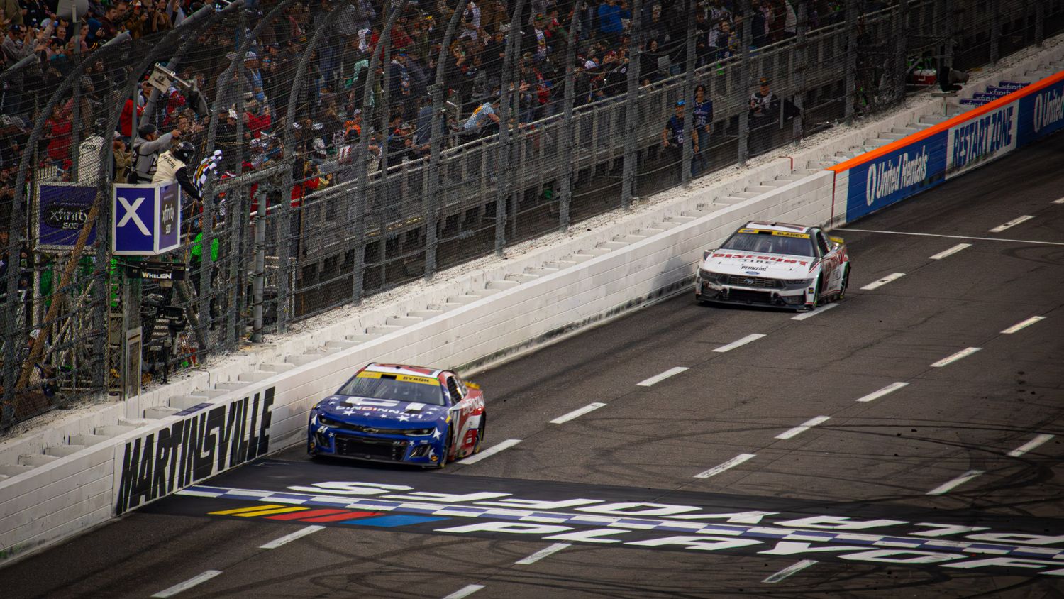 Stock cars race side-by-side down the frontstretch at Martinsville during an exciting finish.