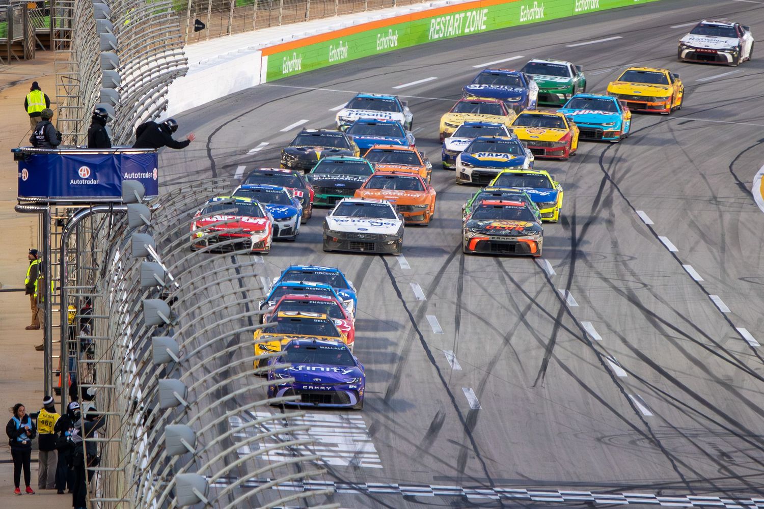 NASCAR race cars spread across EchoPark Speedway during competitive racing action.
