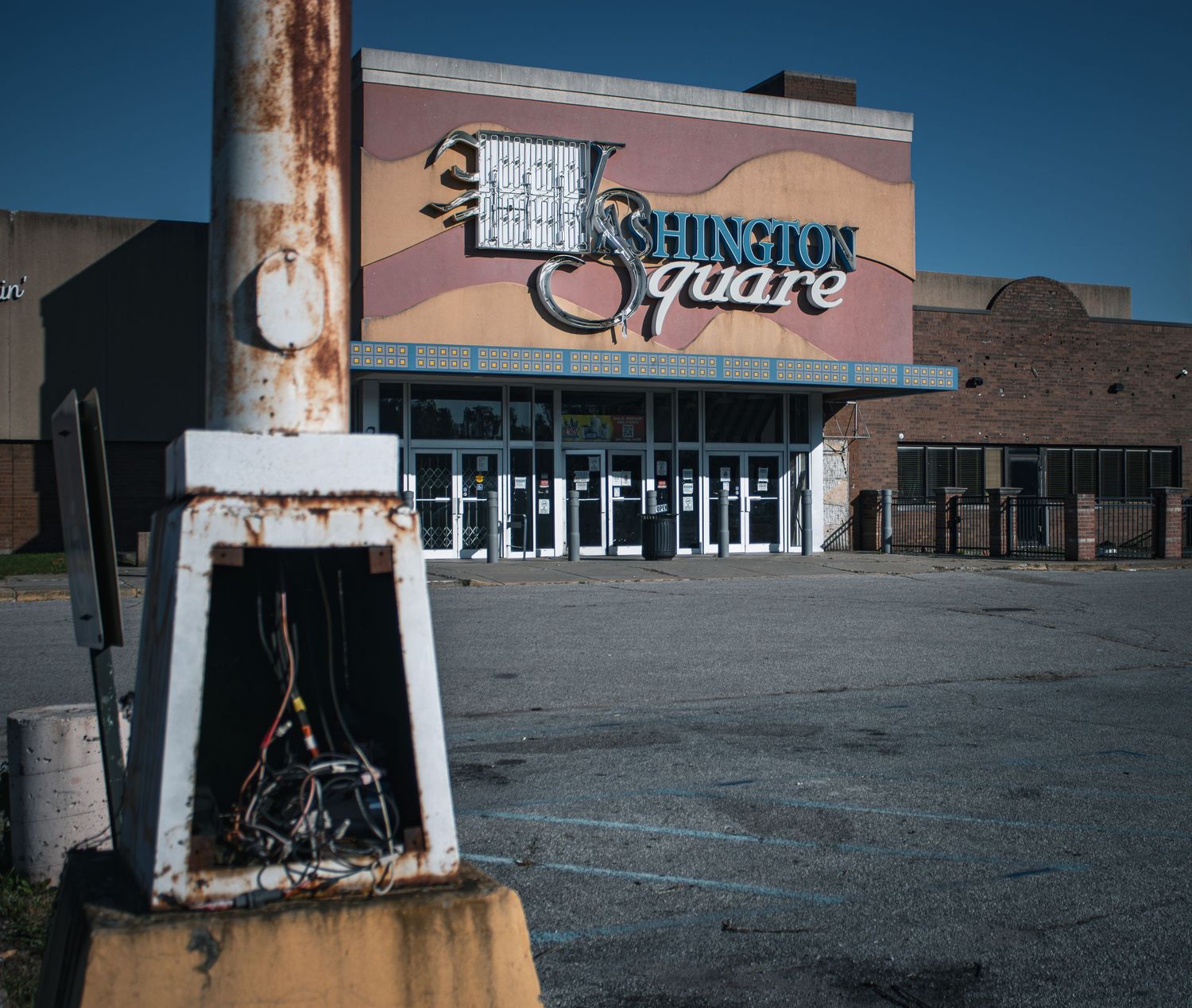 Abandoned storefront of a Burlington retail store with a faded pink sign and empty parking lot.