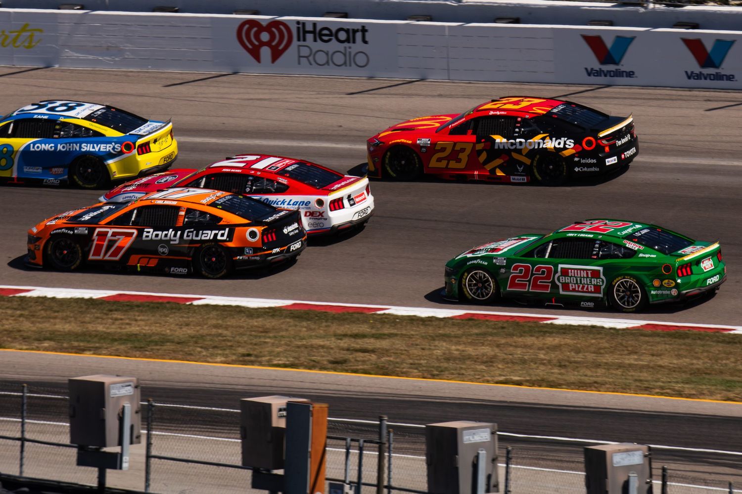NASCAR stock cars racing side by side on an oval track during competition.