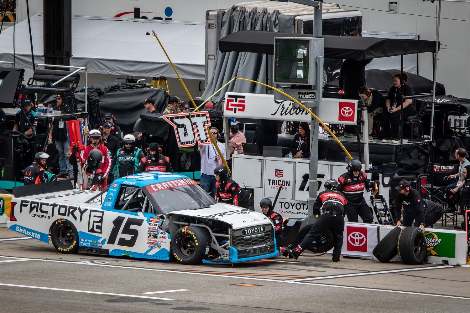 Pit crew members in safety gear perform maintenance on a race car during a pit stop during the Fr8 Racing 208 at EchoPark Speedway on Februa