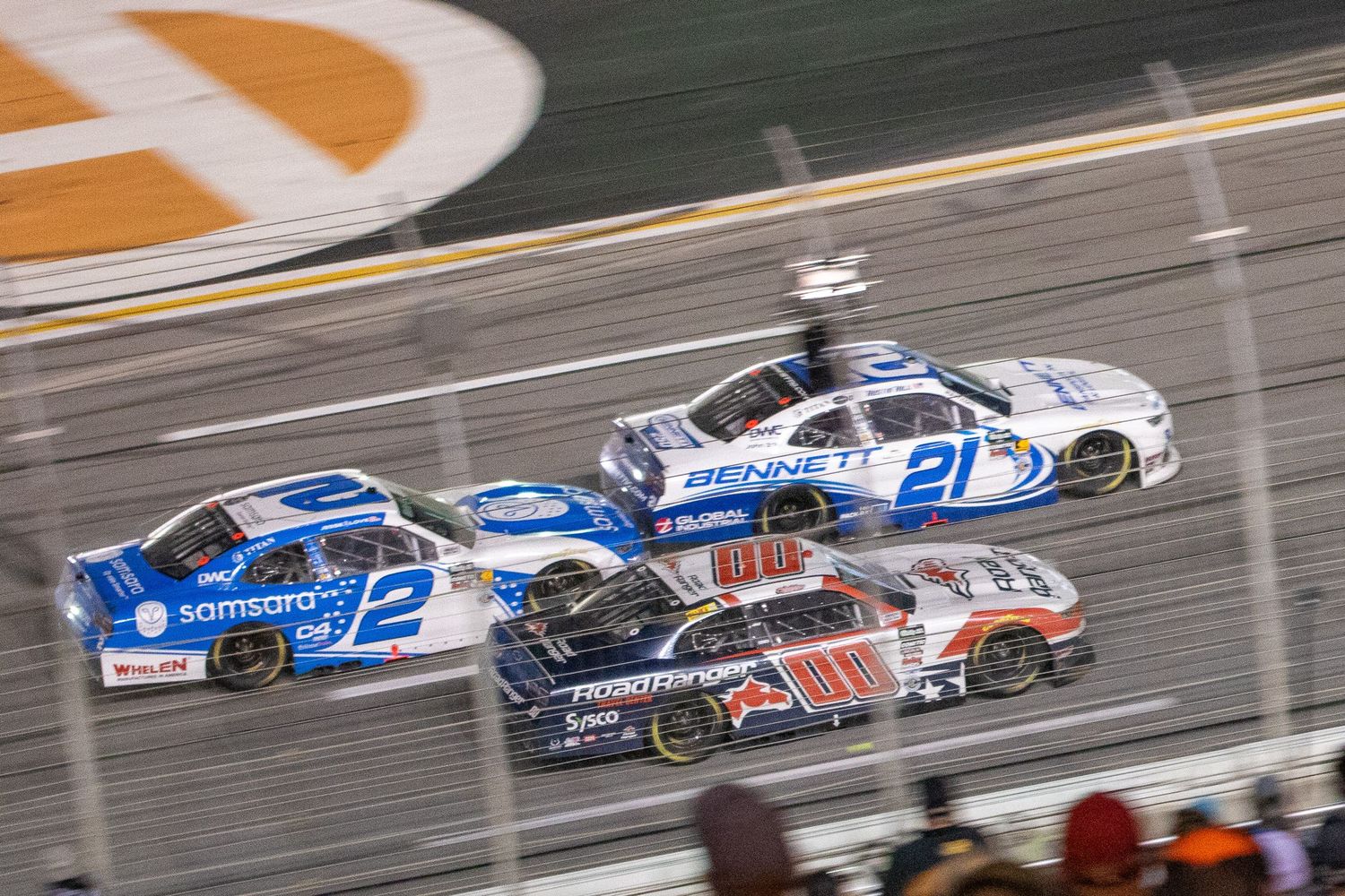 Multiple NASCAR race cars compete under the lights during the Bennet Transportation & Logistics 250 on February 21st 2026