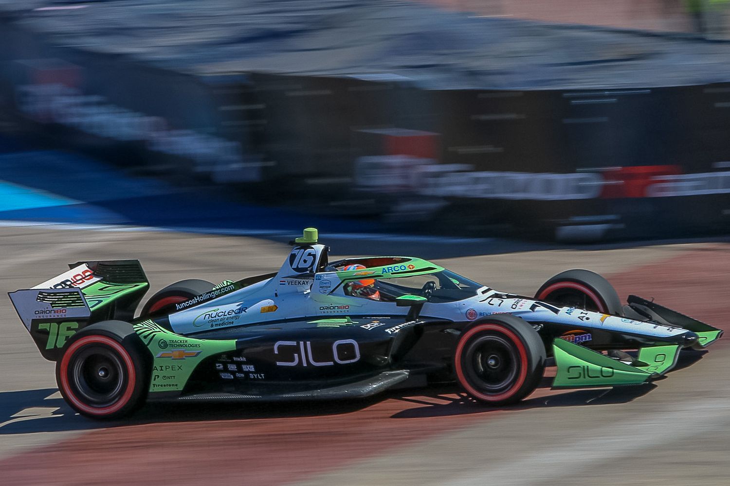 Green and black Formula E race car speeds through a blurred urban racetrack during competition.