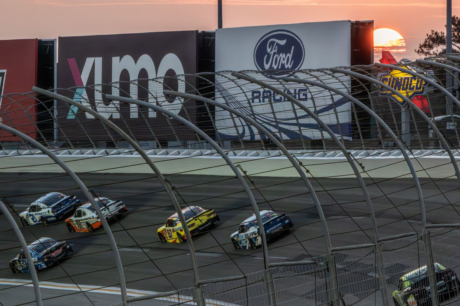 NASCAR vehicles compete on banked turn during the Bennet Transportation & Logistics 250 on February 21st 2026 at sunset