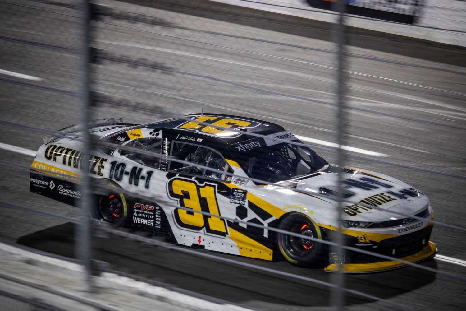 Two NASCAR stock cars battle for position on the speedway during intense racing action.