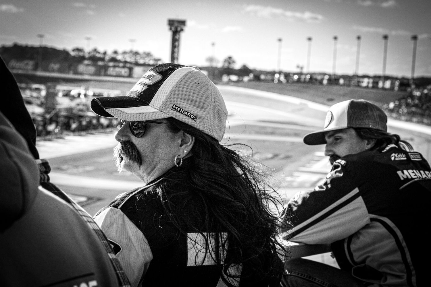 Black and white photo of spectators watching trackside activity at a NASCAR racing event.