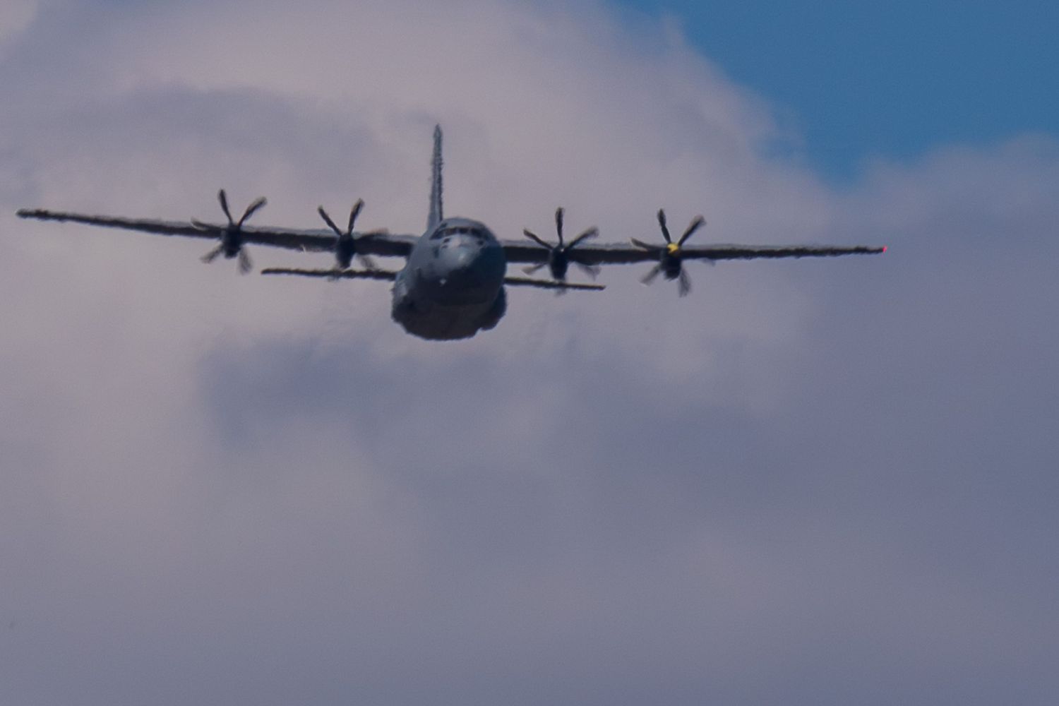 Military transport aircraft flying against a blue sky during a NASCAR race flyover.