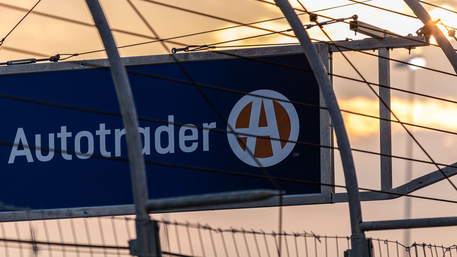 Close-up view of Autotrader logo and branding on NASCAR track signage at dusk.