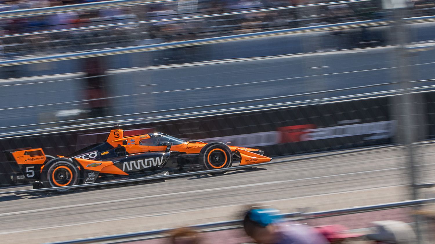 Orange McLaren Formula 1 race car speeds along a racing circuit during a competition event.