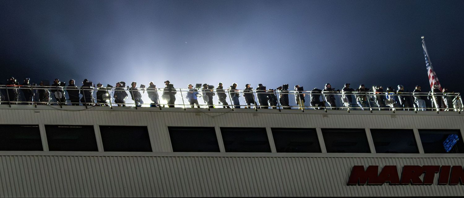 Silhouettes of spectators line up along the top of Martinsville Speedway's grandstand at dusk.