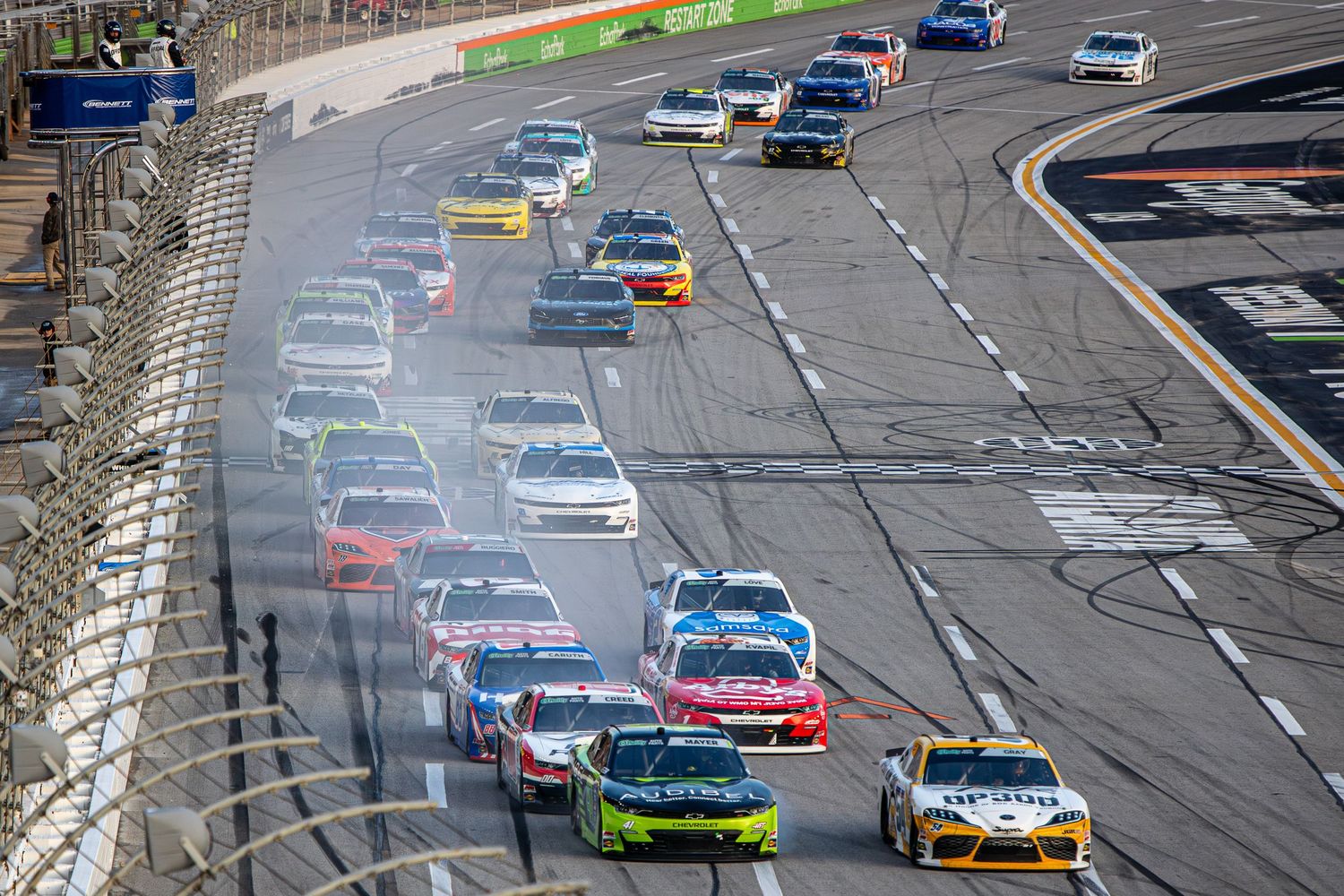 NASCAR stock cars create tire smoke while racing hard during the Bennet Transportation & Logistics 250