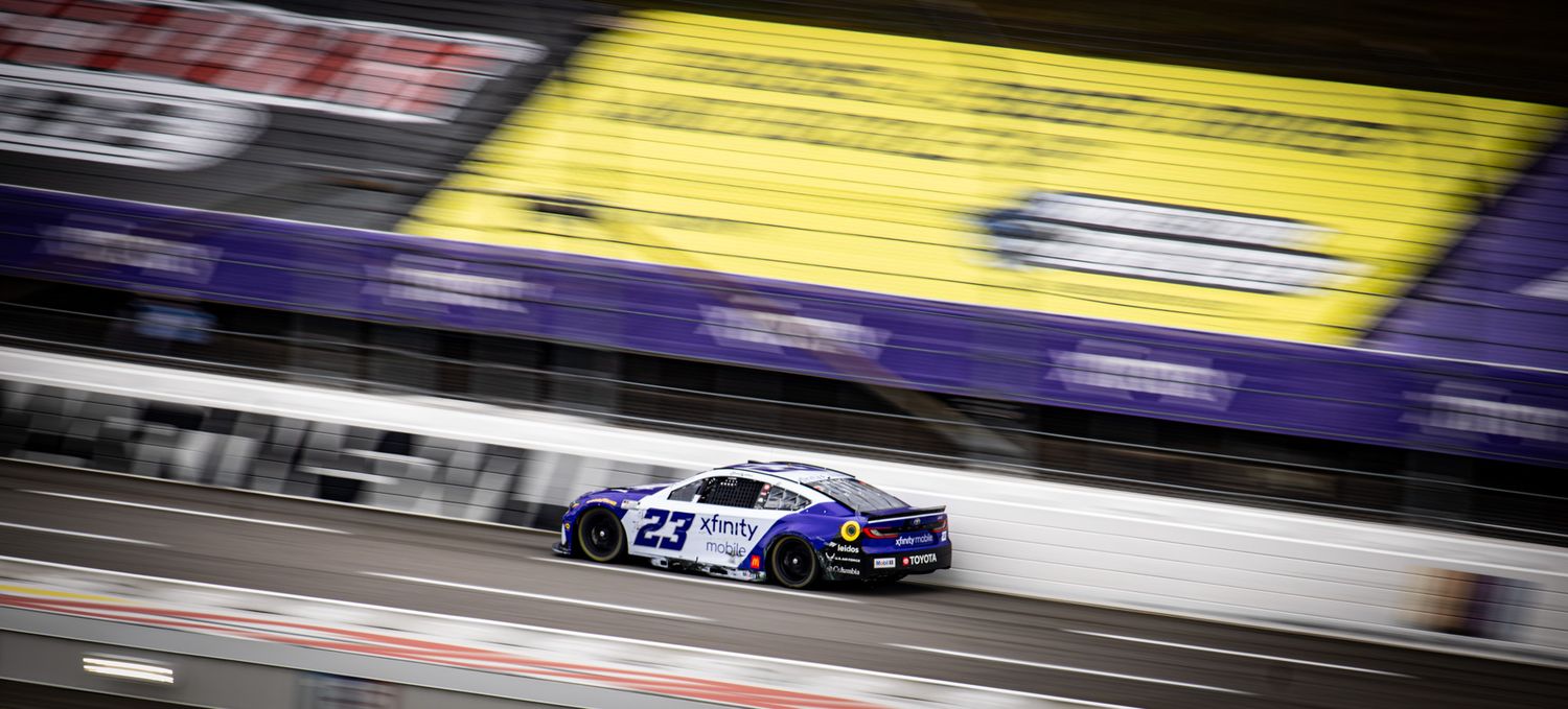 Racing action on track with yellow and blue NASCAR vehicles.