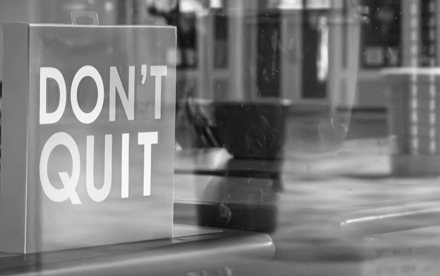 Motivational 'Don't Quit' text displayed on reflective glass window.