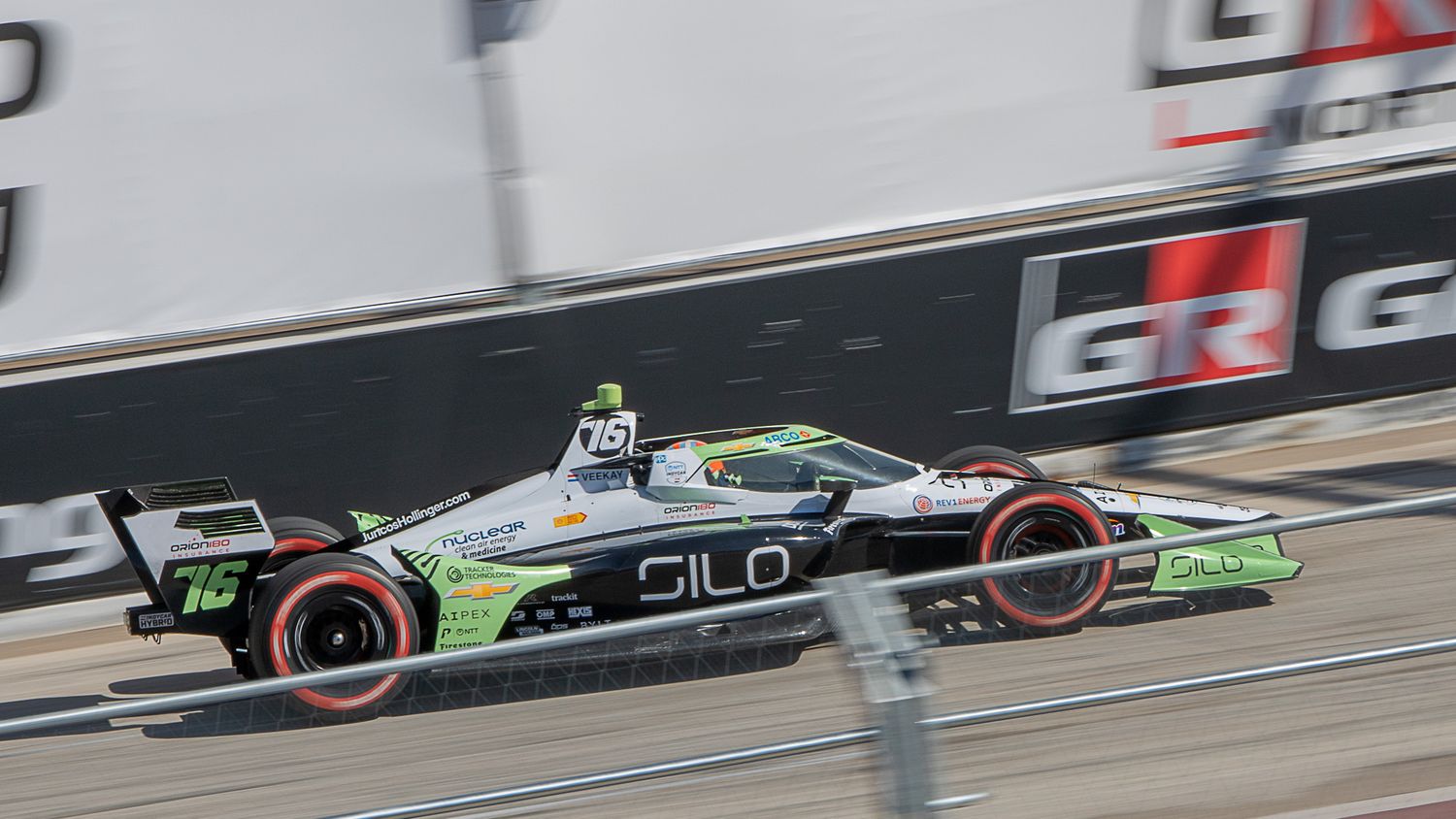 Electric race cars compete on a street track with advertising barriers and grandstands visible along the course.