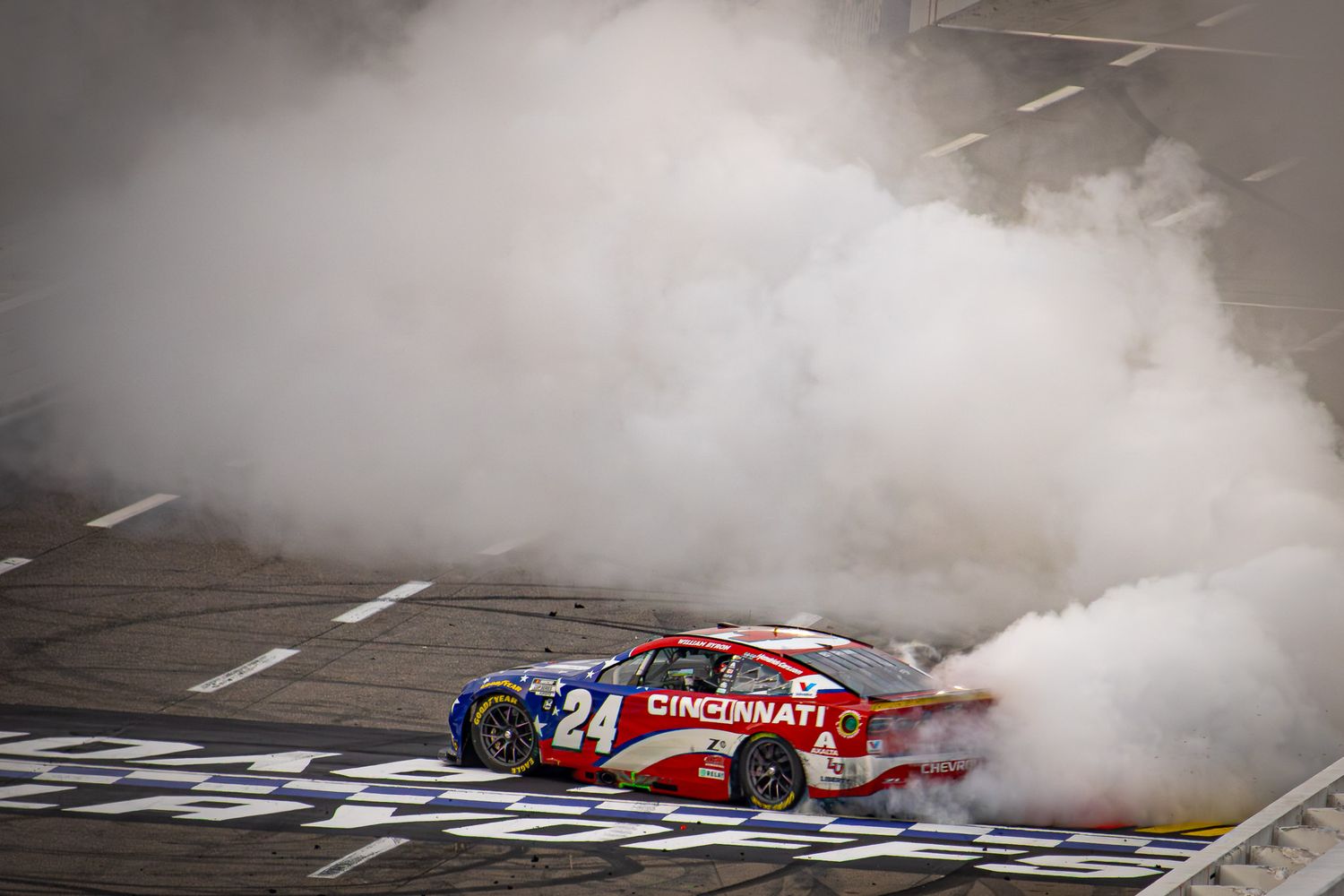 Race car performs celebratory burnout creating dense smoke at the finish line.