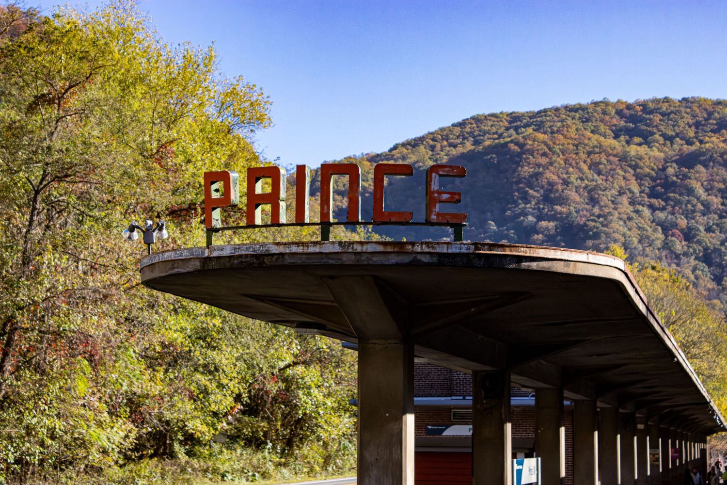 Abandoned retro Palace sign on concrete overhang against autumn mountain landscape.