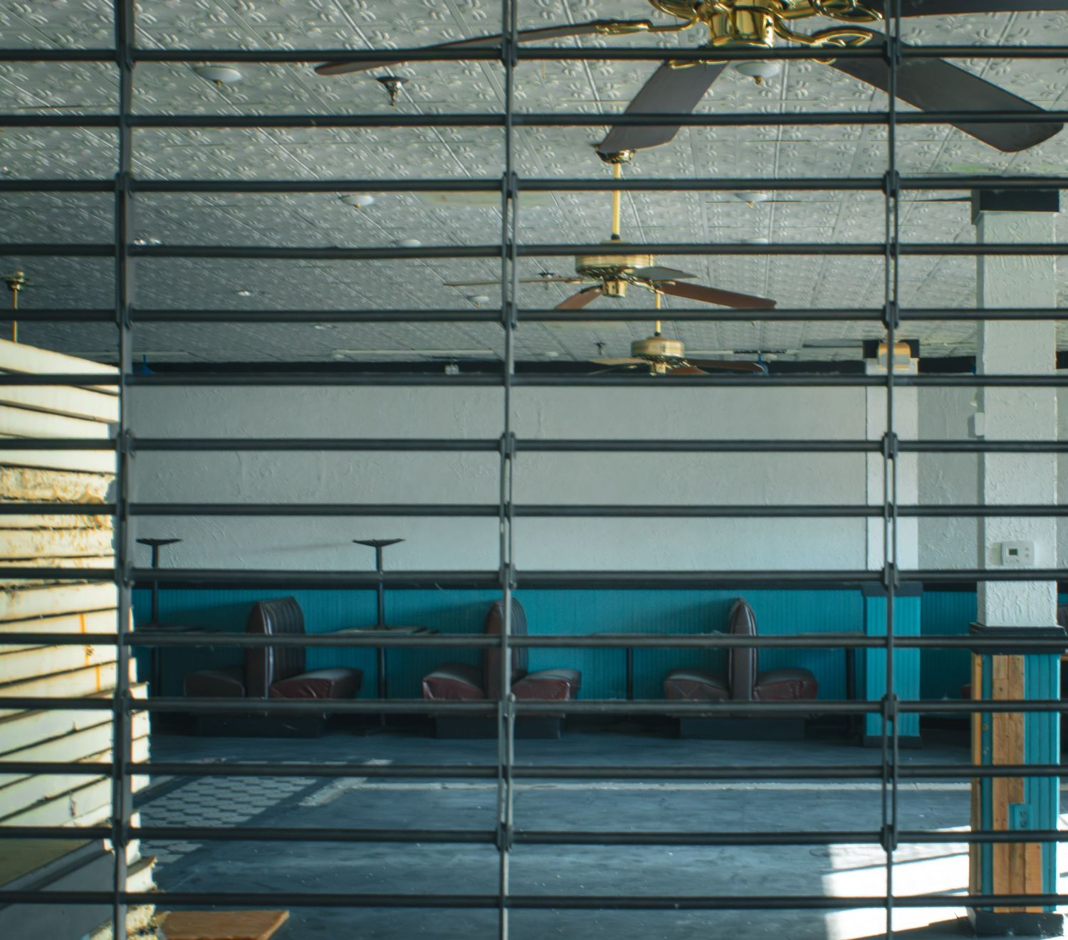 Interior view of ceiling fans through venetian blinds in an empty room.