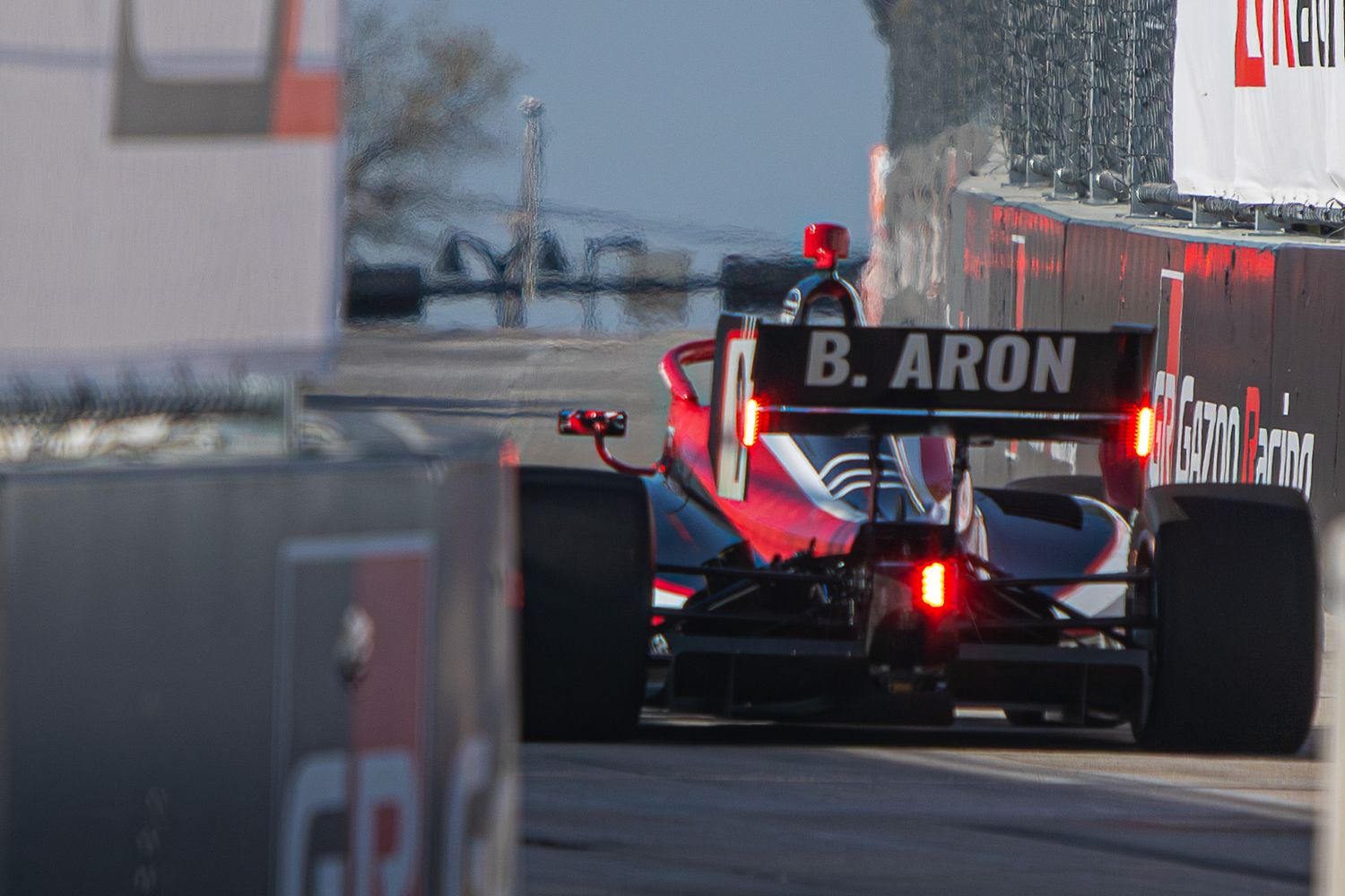 Formula E racing cars speed through a city circuit with buildings and barriers visible in the background.