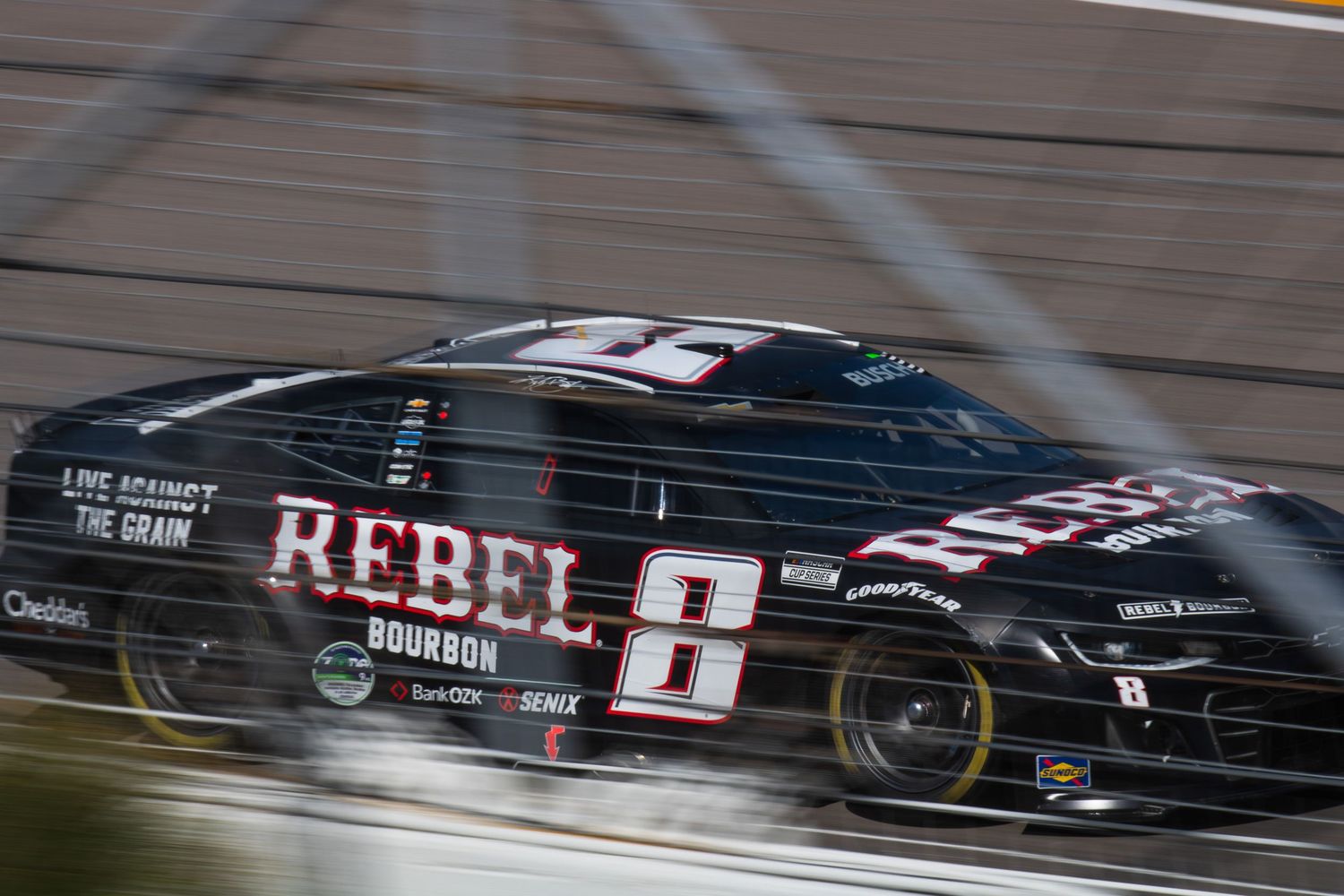 Black Rebel racing car speeds past competitors during a NASCAR race.