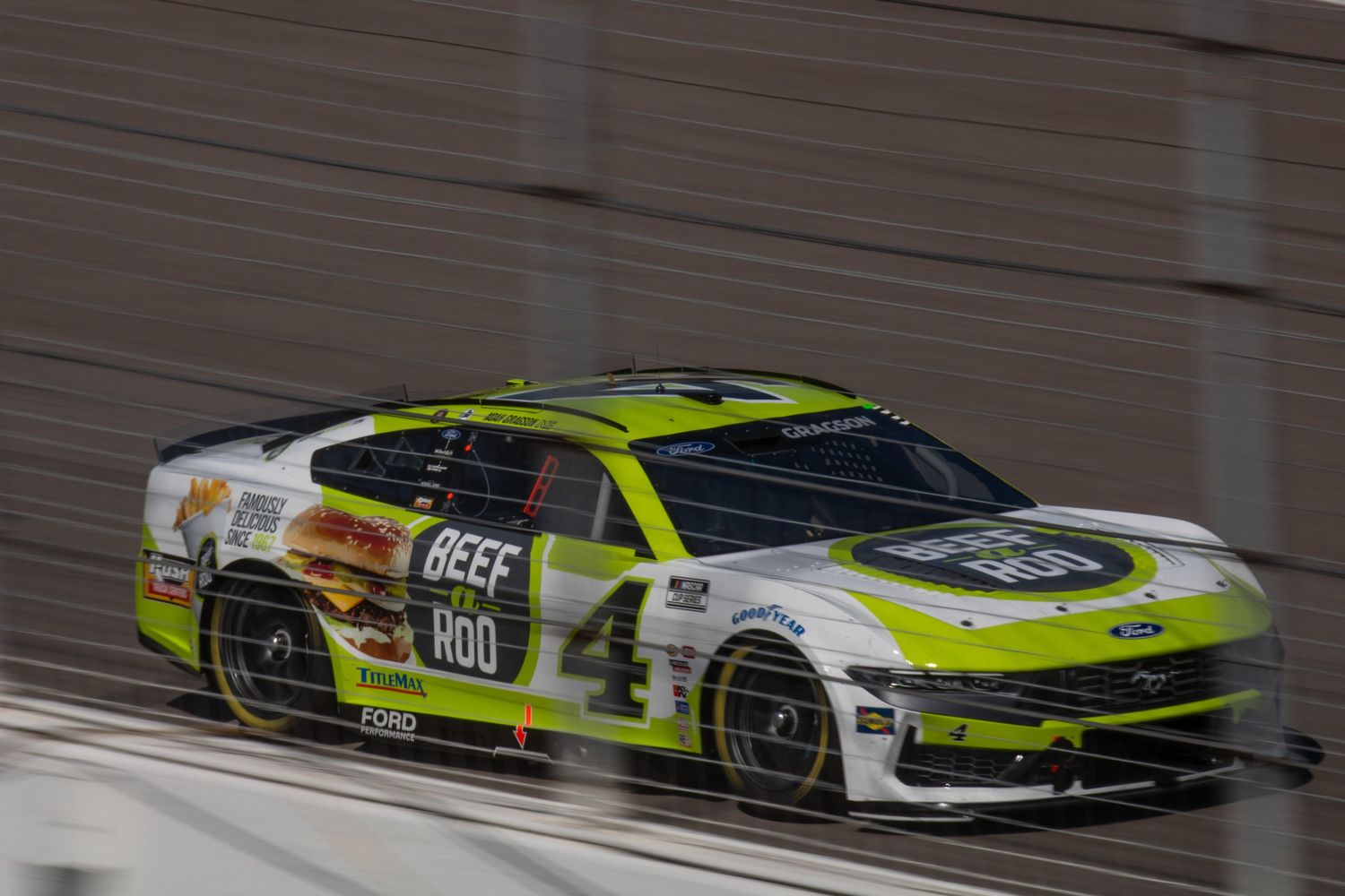 Neon green and white race cars battle for position during a NASCAR event.
