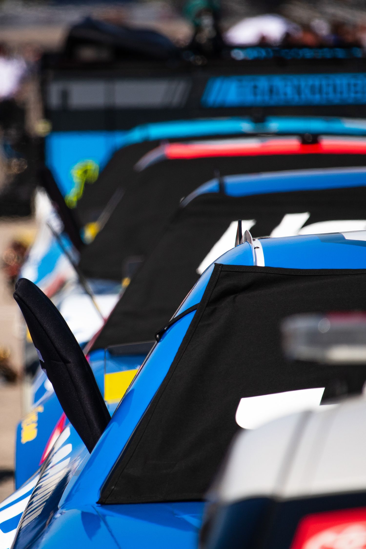NASCAR stock cars featuring blue and white paint schemes parked in formation at a race track.