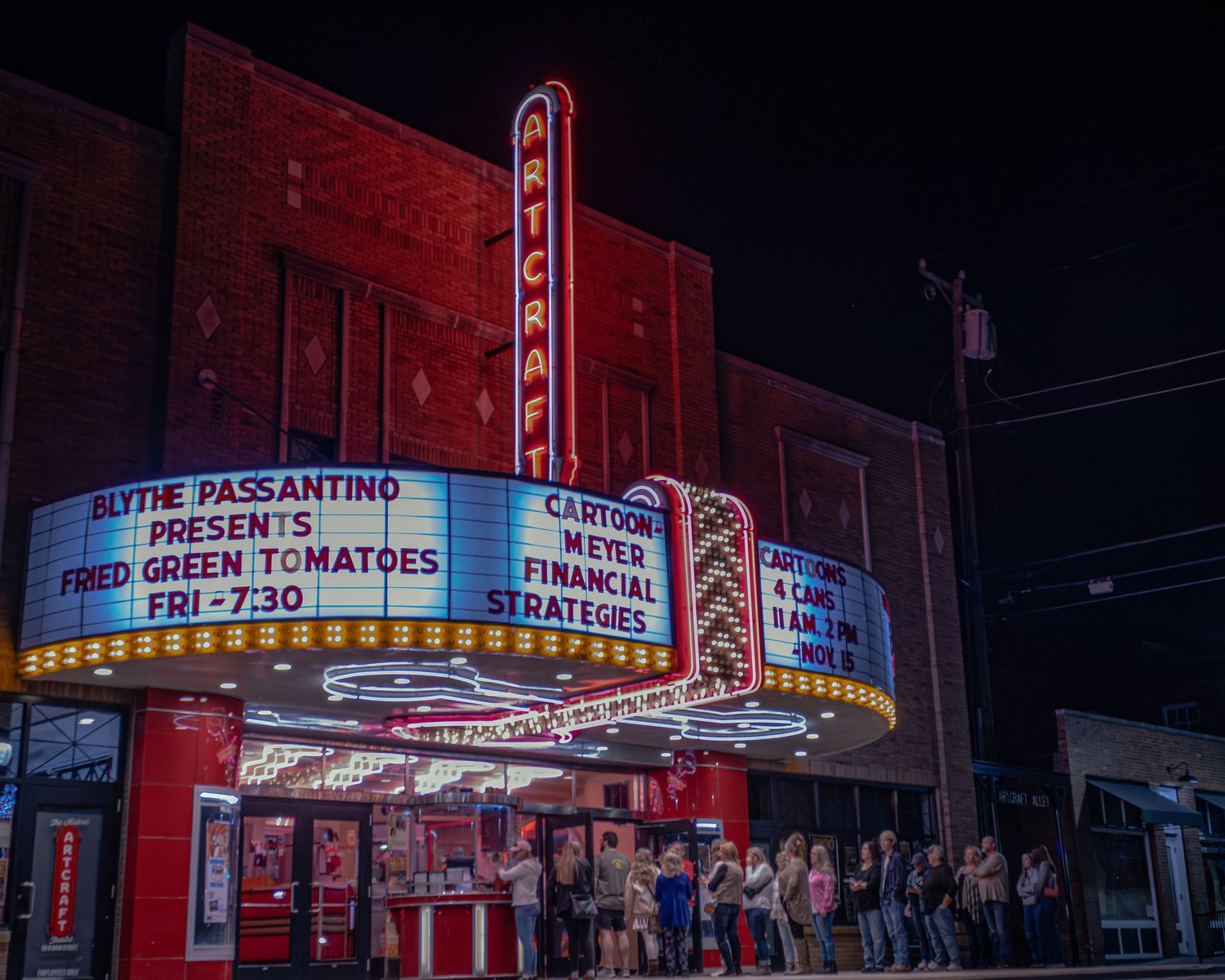 Retro cinema marquee with red neon lights advertising movie showtimes.