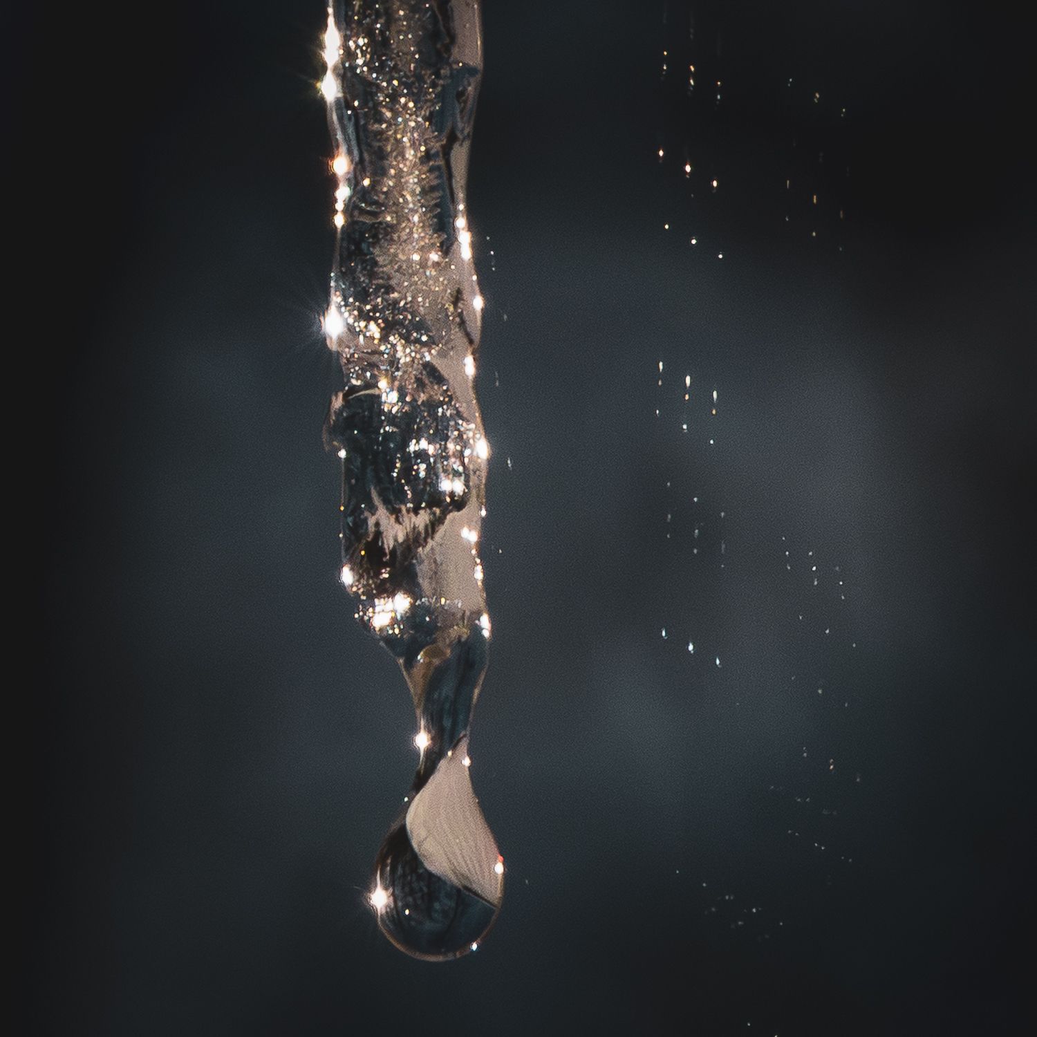 Detailed view of thawing ice formations with scattered water drops against black background.