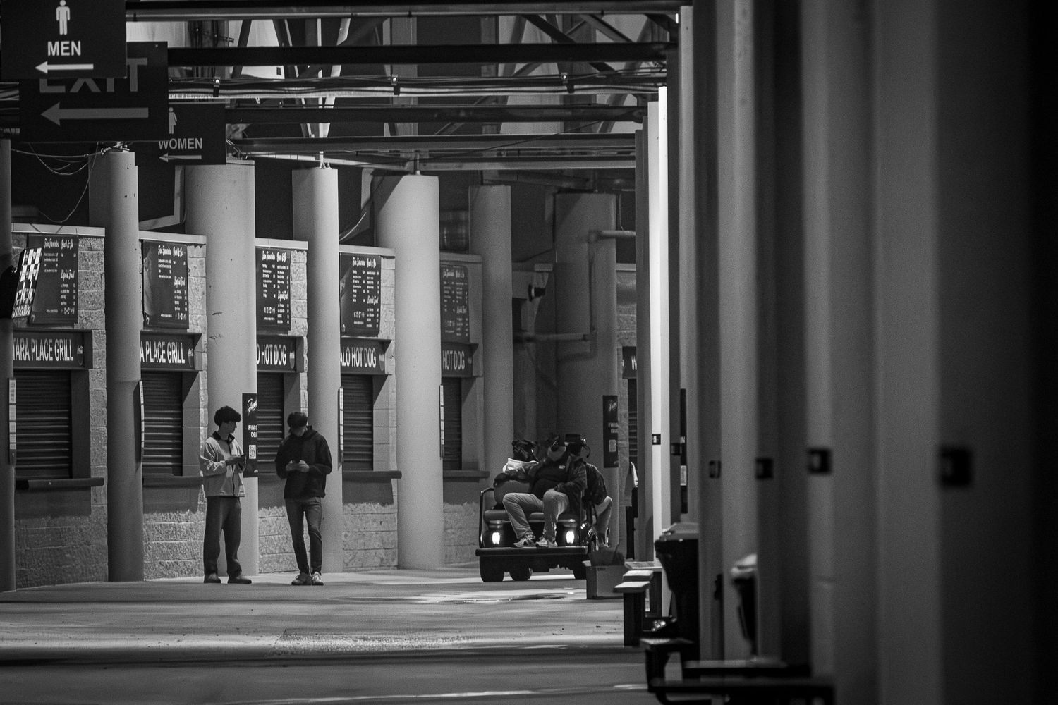 Black and white architectural photo of empty stadium columns and hallways.