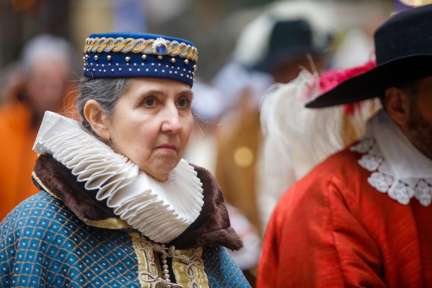 People wearing Renaissance-style costumes with ruffled collars participate in a historical reenactment.