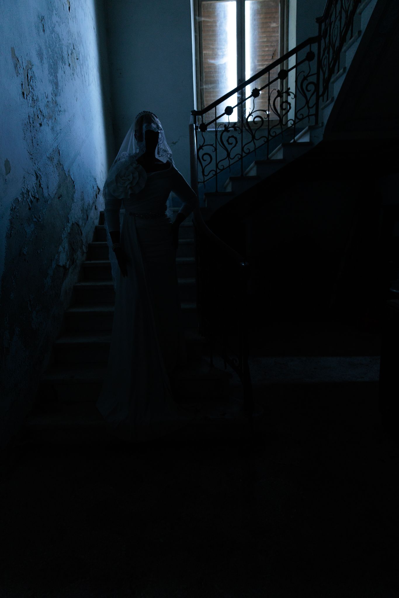 Silhouette of bride in dark stairwell creates moody atmospheric wedding photo.
