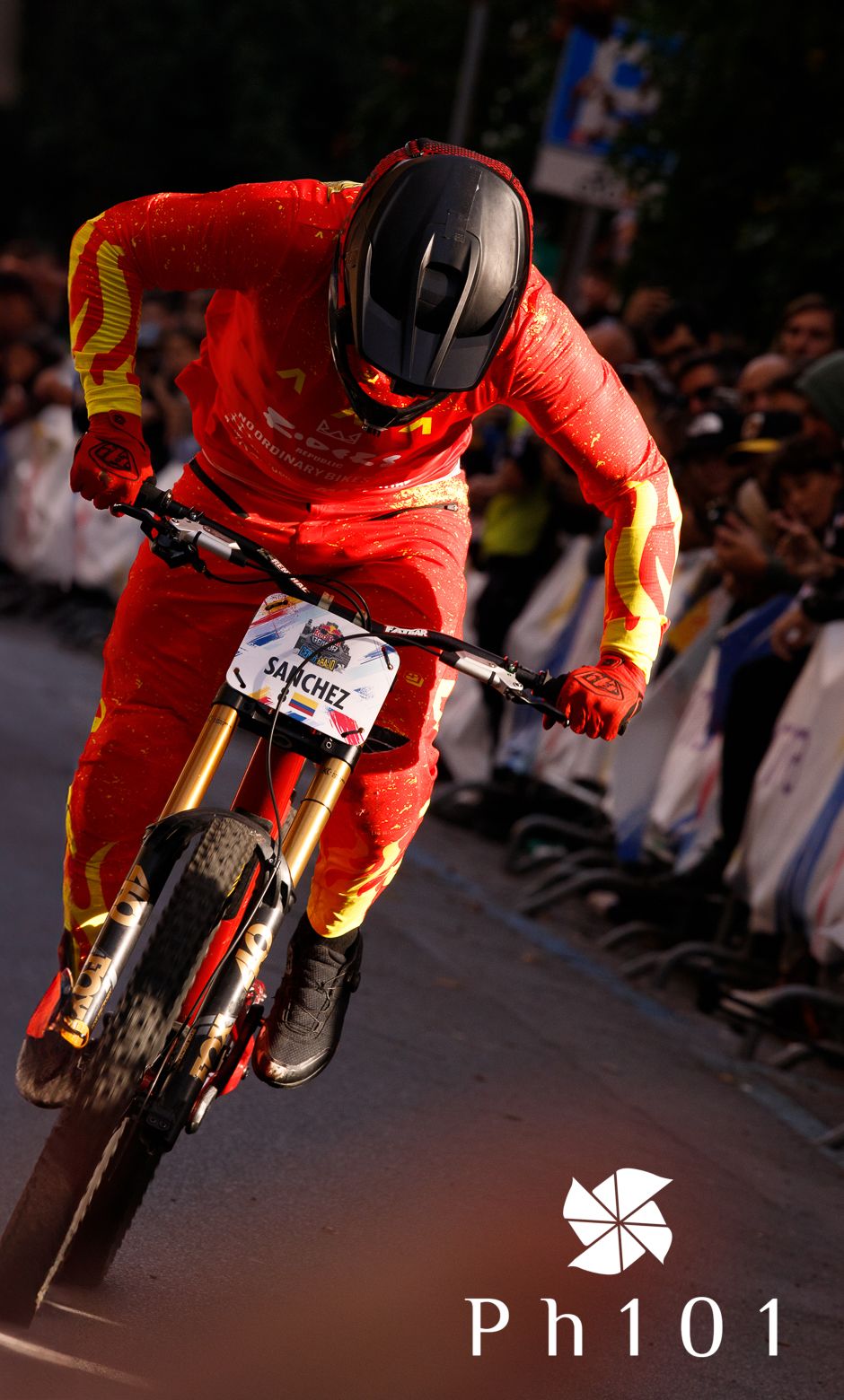 Motorcyclist in red racing suit performing low-angle turn on indoor track.